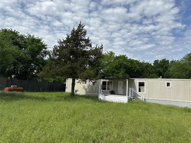 rear view of property with a lawn, covered porch, and fence