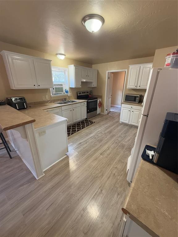 30738 NW Reno Rd, Hinton, OK 73047 - kitchen featuring a peninsula, under cabinet range hood, light wood-style flooring, white cabinets, and appliances with stainless steel finishes