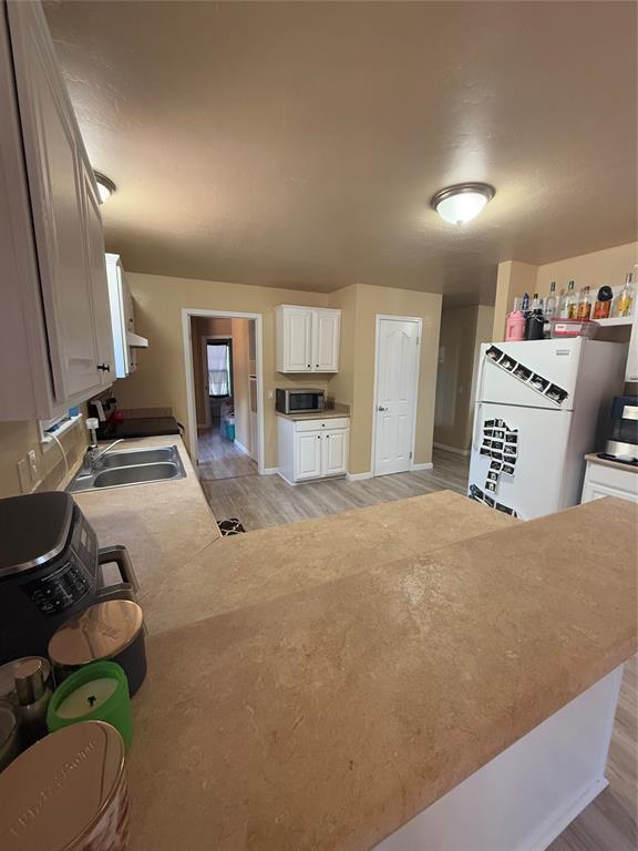 30738 NW Reno Rd, Hinton, OK 73047 - kitchen with stainless steel microwave, freestanding refrigerator, a sink, and light wood-type flooring