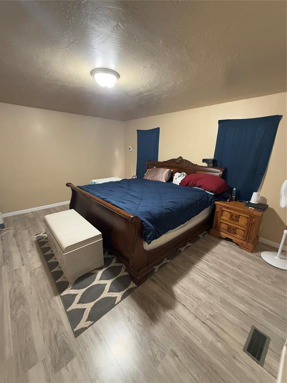 30738 NW Reno Rd, Hinton, OK 73047 - bedroom featuring a textured ceiling, visible vents, wood finished floors, and baseboards
