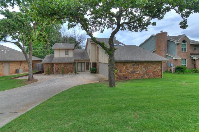 904 Carfax Rd, Edmond, OK 73034 - view of front of house featuring driveway, a front lawn, stone siding, and roof with shingles
