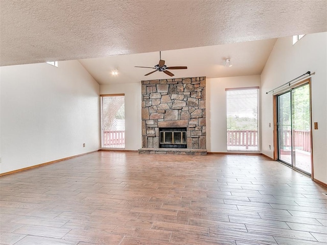 904 Carfax Rd, Edmond, OK 73034 - unfurnished living room with lofted ceiling, a textured ceiling, a ceiling fan, wood finished floors, and a fireplace