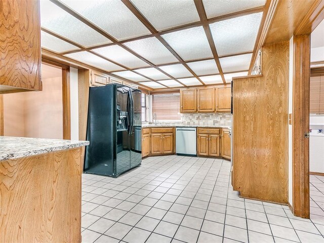 904 Carfax Rd, Edmond, OK 73034 - kitchen with black refrigerator with ice dispenser, dishwasher, light tile patterned floors, brown cabinetry, and decorative backsplash
