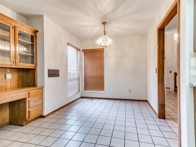 904 Carfax Rd, Edmond, OK 73034 - unfurnished dining area featuring a chandelier, light tile patterned floors, and built in desk