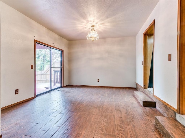 904 Carfax Rd, Edmond, OK 73034 - unfurnished room with a chandelier, wood finished floors, and a textured ceiling