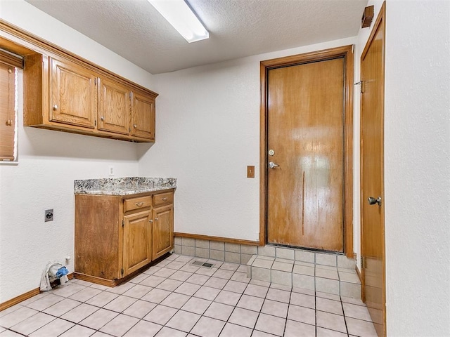 904 Carfax Rd, Edmond, OK 73034 - laundry room with electric dryer hookup, cabinet space, a textured ceiling, and light tile patterned flooring