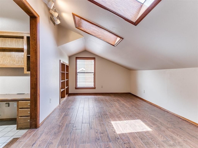 904 Carfax Rd, Edmond, OK 73034 - bonus room with a skylight, vaulted ceiling, and wood finished floors