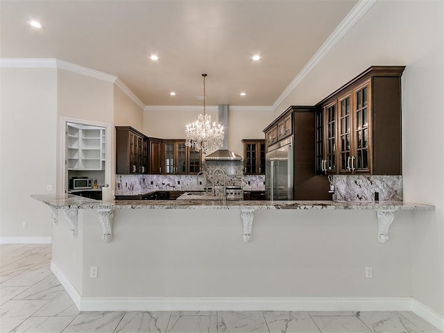 6209 Lakewood Ridge Rd, Edmond, OK 73013 - kitchen featuring wall chimney range hood, built in fridge, light marble finish floors, light stone counters, and a breakfast bar area