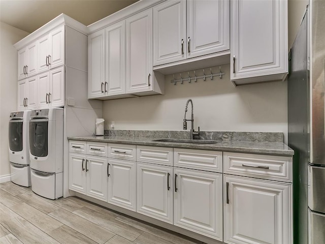 6209 Lakewood Ridge Rd, Edmond, OK 73013 - washroom with cabinet space, separate washer and dryer, light wood finished floors, and bar with sink