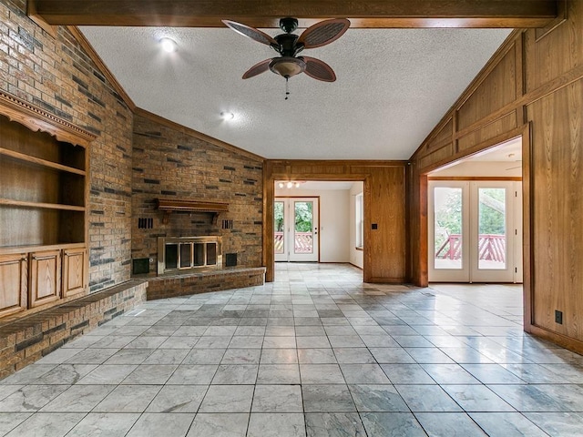 908 Carfax Rd, Edmond, OK 73034 - unfurnished living room featuring lofted ceiling, french doors, wood walls, a ceiling fan, and a textured ceiling