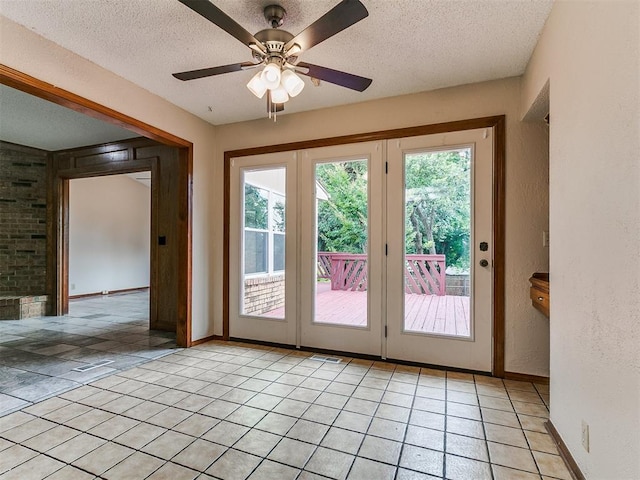 908 Carfax Rd, Edmond, OK 73034 - doorway featuring a textured ceiling, light tile patterned floors, a ceiling fan, and a textured wall