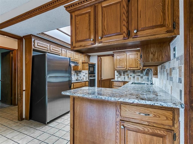 908 Carfax Rd, Edmond, OK 73034 - kitchen with appliances with stainless steel finishes, backsplash, light tile patterned flooring, a peninsula, and brown cabinetry