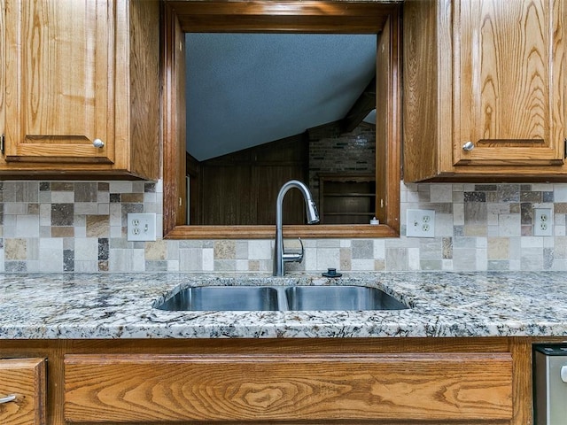 908 Carfax Rd, Edmond, OK 73034 - kitchen featuring backsplash, brown cabinetry, vaulted ceiling, and light stone counters
