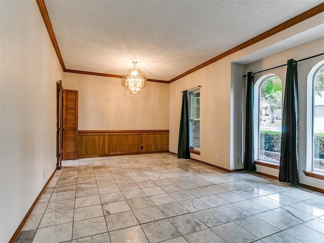 908 Carfax Rd, Edmond, OK 73034 - empty room featuring crown molding, a textured ceiling, a chandelier, light marble finish floors, and wooden walls