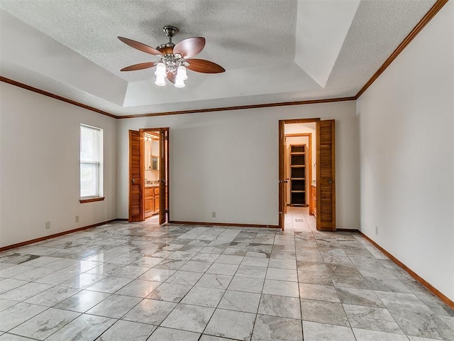 908 Carfax Rd, Edmond, OK 73034 - spare room featuring a tray ceiling, a ceiling fan, a textured ceiling, ornamental molding, and light marble finish floors