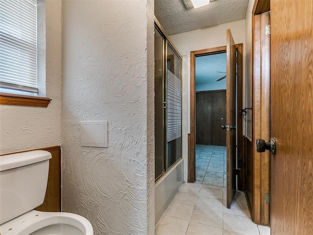 908 Carfax Rd, Edmond, OK 73034 - bathroom with tile patterned floors, a textured ceiling, shower / bath combination with glass door, and a textured wall