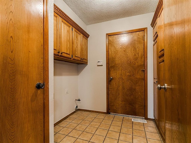908 Carfax Rd, Edmond, OK 73034 - washroom with a textured ceiling, cabinet space, and light tile patterned flooring