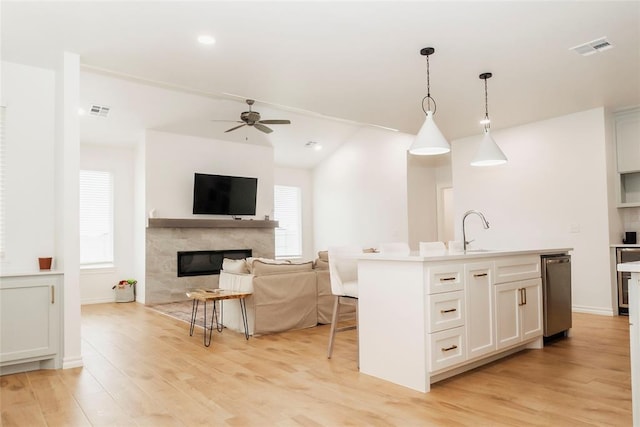 7310 S Brookwater Way, Stillwater, OK 74074 - kitchen featuring a premium fireplace, stainless steel dishwasher, visible vents, and light wood-style floors