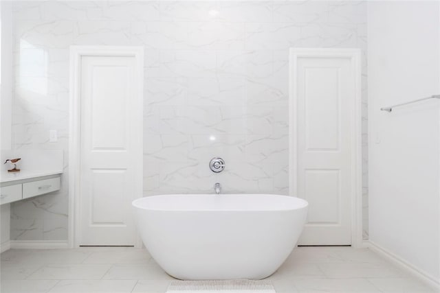 7310 S Brookwater Way, Stillwater, OK 74074 - bathroom with baseboards, marble finish floor, and a freestanding tub