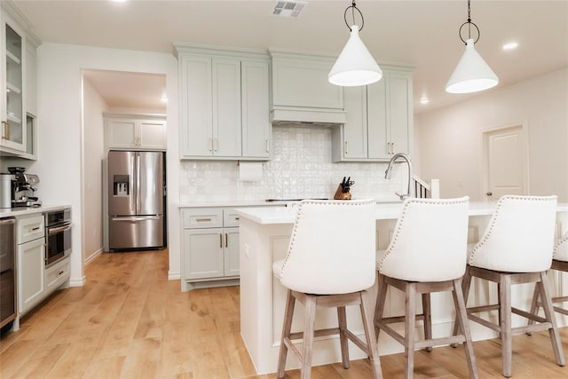 7310 S Brookwater Way, Stillwater, OK 74074 - kitchen with stainless steel appliances, tasteful backsplash, a kitchen breakfast bar, visible vents, and light countertops
