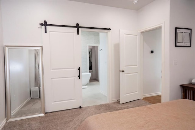 7310 S Brookwater Way, Stillwater, OK 74074 - carpeted bedroom with ensuite bath, a barn door, and baseboards