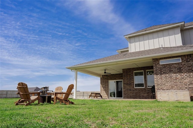 7310 S Brookwater Way, Stillwater, OK 74074 - back of property with a yard, board and batten siding, brick siding, a fire pit, and roof with shingles