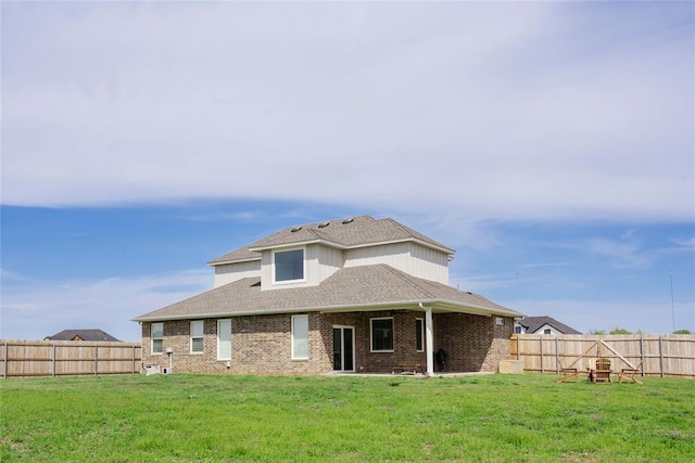 7310 S Brookwater Way, Stillwater, OK 74074 - back of property with a fenced backyard, a shingled roof, brick siding, and a lawn