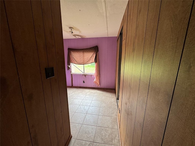 spare room featuring wood walls and light tile patterned floors