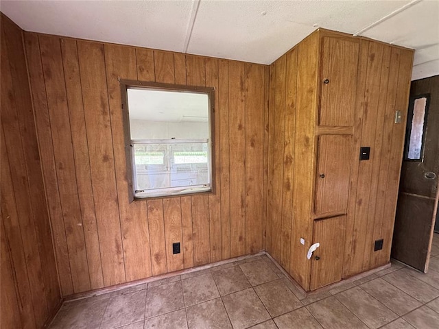 tiled spare room featuring wood walls