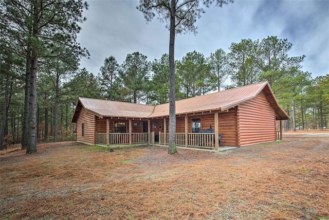 view of front of property featuring log siding, covered porch, and metal roof