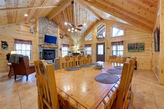 dining space featuring light tile patterned floors, wooden ceiling, wooden walls, healthy amount of natural light, and high vaulted ceiling