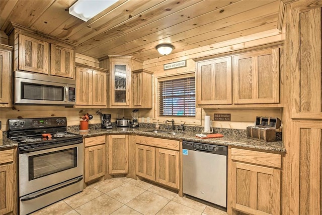 kitchen with stainless steel appliances, a sink, light tile patterned flooring, wood ceiling, and glass insert cabinets