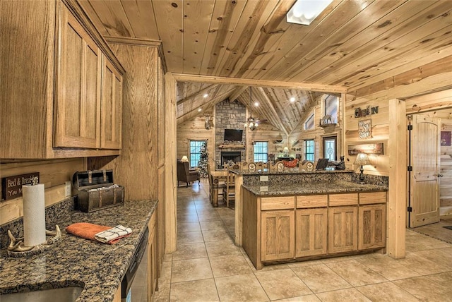 kitchen featuring wooden walls, open floor plan, wood ceiling, stainless steel dishwasher, and a stone fireplace