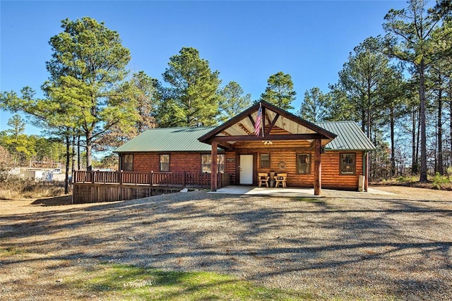 rear view of house featuring metal roof, a standing seam roof, and faux log siding