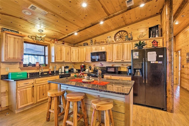 kitchen with black appliances, a sink, lofted ceiling, light wood-style floors, and a kitchen bar