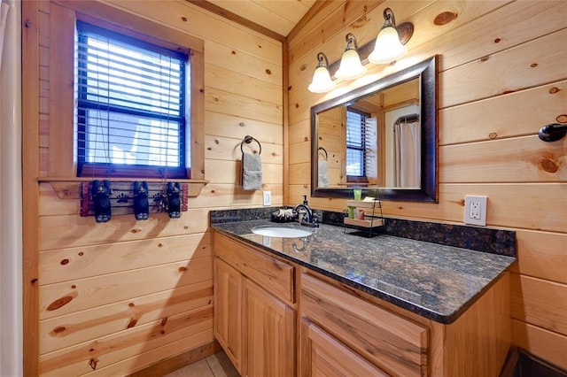 bathroom with wooden walls, vanity, and tile patterned floors