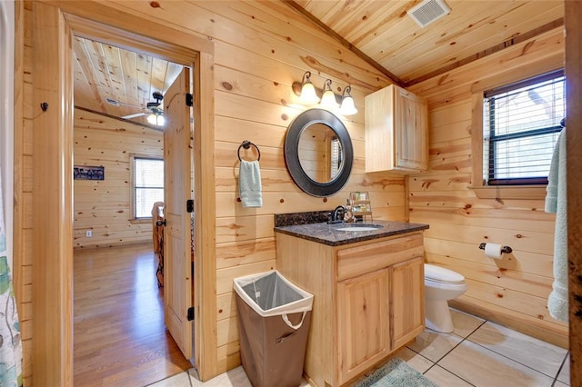 bathroom featuring vaulted ceiling, wood walls, wooden ceiling, toilet, and vanity