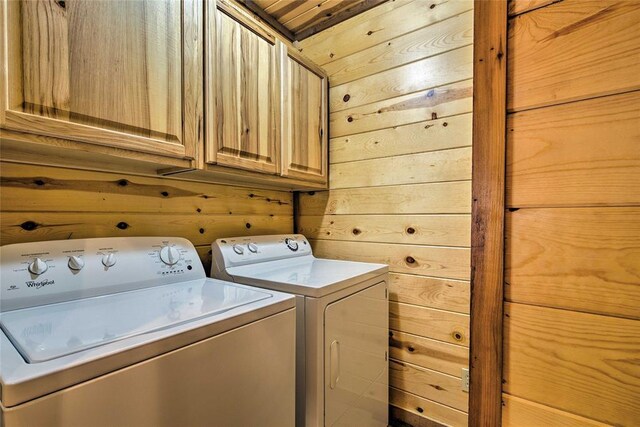 laundry area with cabinet space, independent washer and dryer, and wooden walls