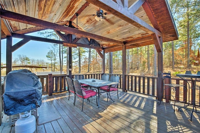 wooden terrace with outdoor dining space and ceiling fan