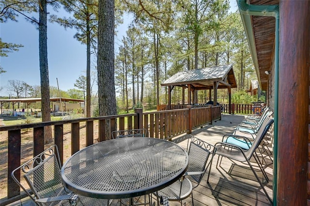 wooden terrace with outdoor dining area and a gazebo