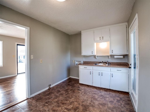 6401 Anderson, Oklahoma City, OK 73149 - kitchen featuring a sink, white cabinetry, a textured ceiling, and baseboards