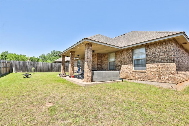 view of side of home featuring a yard, central AC, roof with shingles, and a fenced backyard