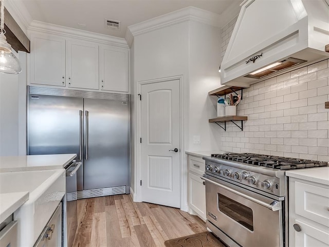 8509 NW 125th St, Oklahoma City, OK 73142 - kitchen with high end appliances, range hood, light countertops, white cabinets, and light wood finished floors