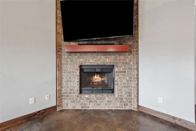 detailed view of concrete flooring, baseboards, and a brick fireplace