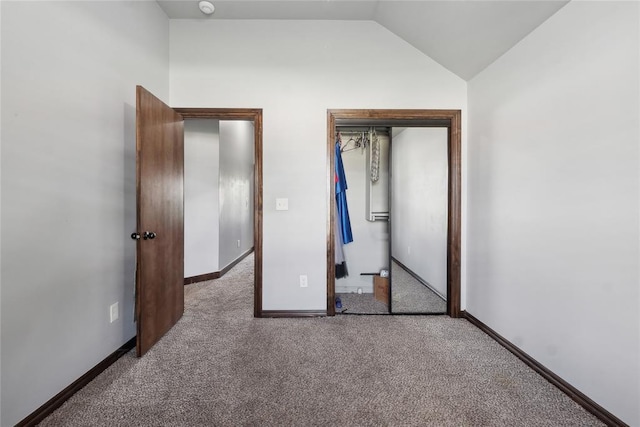 unfurnished bedroom featuring vaulted ceiling, carpet floors, baseboards, and a closet