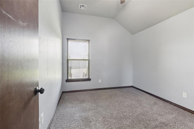 empty room featuring carpet floors, vaulted ceiling, and baseboards