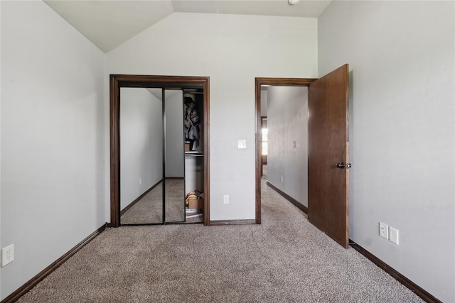 unfurnished bedroom featuring carpet floors, vaulted ceiling, a closet, and baseboards