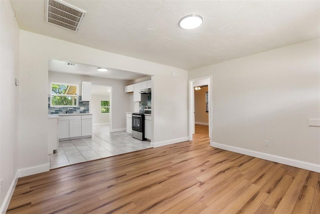 1225 NW 99th St, Oklahoma City, OK 73114 - unfurnished living room with light wood-style flooring, baseboards, and a sink