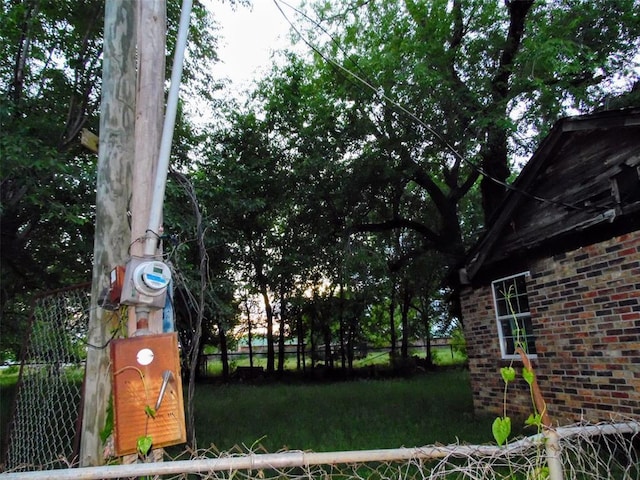 exterior view of fence, electric meter, and brick siding