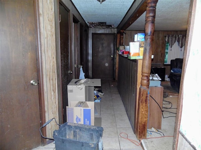 hall with light tile patterned floors and wood walls